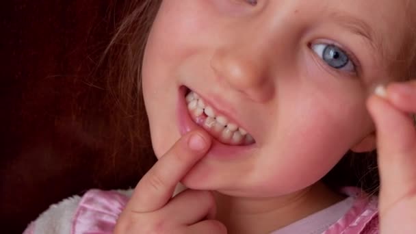 かわいい未就学児は彼女の低いミルクの歯と笑顔をぐらつかせます 永久4K映像暗い背景によって決定的な歯の交換 怖いです女の子6 7歳持っていますIncisorを失っています — ストック動画