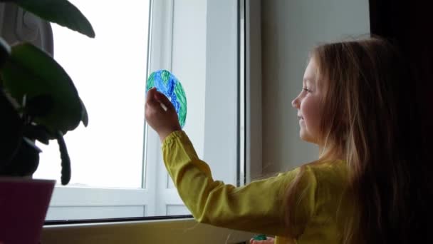 Χαριτωμένο Κοριτσάκι Ζωγραφίζει Τον Πλανήτη Στο Παράθυρο Στο Σπίτι Χαρούμενο — Αρχείο Βίντεο