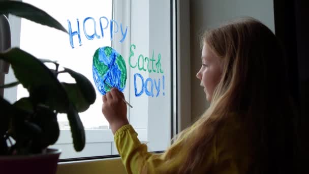 Nin Penceresine Gezegeni Boyayan Sevimli Küçük Kız Nisan Dünya Günü — Stok video
