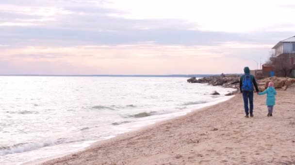 父と娘の空のビーチで実行して歩く笑顔 本物の人生だ 海の水紫色の夕日の空と風景海の風景 ハッピーアクティブ家族楽しい旅行を持っている新しい通常のCovid — ストック動画