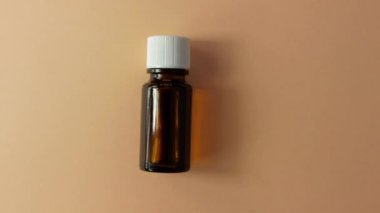 Bitki özlü cam şişe bej çiçekli arka plan. Alternatif tıp rahatlatıcı spa aromaterapi vücut tedavisi güzellik kozmetik ürün şablonu. Masaj yağı teni özü