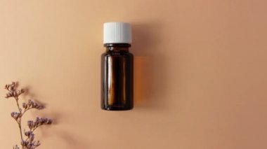 Bitki özlü cam şişe bej çiçekli arka plan. Alternatif tıp rahatlatıcı spa aromaterapi vücut tedavisi güzellik kozmetik ürün şablonu. Masaj yağı teni özü