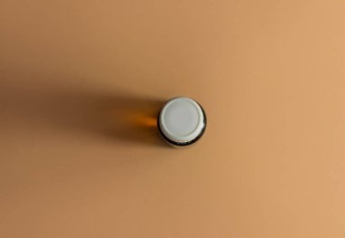 Bitki özlü cam şişe bej çiçekli arka plan. Alternatif tıp rahatlatıcı spa aromaterapi vücut tedavisi güzellik kozmetik ürün şablonu. Masaj yağı teni özü