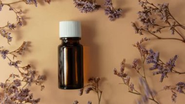 Bitki özlü cam şişe bej çiçekli arka plan. Alternatif tıp rahatlatıcı spa aromaterapi vücut tedavisi güzellik kozmetik ürün şablonu. Masaj yağı teni özü