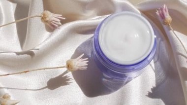 Mavi cam krem kavanozu, çiçek desenli ipek kumaş. Doğal cilt nemlendirici. Kozmetik, sağlıklı cilt.