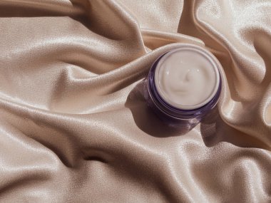 Mavi cam krem kavanozu, çiçek desenli ipek kumaş. Doğal cilt nemlendirici. Kozmetik, sağlıklı cilt.