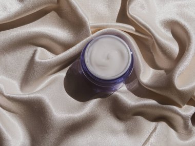 Mavi cam krem kavanozu, çiçek desenli ipek kumaş. Doğal cilt nemlendirici. Kozmetik, sağlıklı cilt.