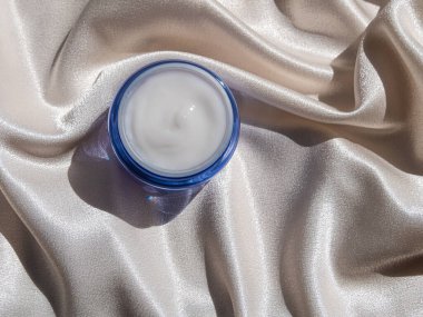 Mavi cam krem kavanozu, çiçek desenli ipek kumaş. Doğal cilt nemlendirici. Kozmetik, sağlıklı cilt.