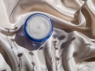 Mavi cam krem kavanozu, çiçek desenli ipek kumaş. Doğal cilt nemlendirici. Kozmetik, sağlıklı cilt.