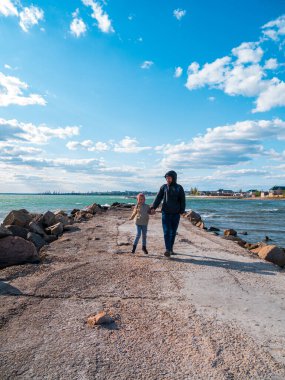Baba ve kızı boş sahilde koşarken gülümsüyor. Hayat tarzı gerçek insanlar. Manzaralı deniz manzarası canlı mavi deniz suyu gökyüzü. Mutlu aktif aile tatil gezisi duvar kağıdında eğleniyor.