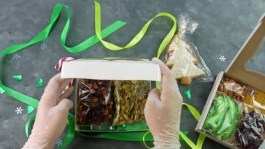 Kız, ayrı ayrı paketlenmiş kurutulmuş meyve fındıklarıyla hediye paketini paketliyor. Sağlıklı beslenme. Noel kutlaması bayramları kadınların ellerinde eko-doğal atıştırmalıklar hazırlamak. Bilinçli tüketim tatlısı.