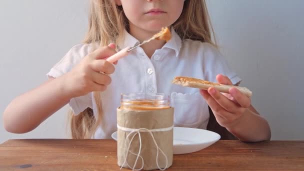 Niño Comiendo Pan Crujiente Con Mantequilla Maní Sentado Cocina Casa — Vídeo de stock