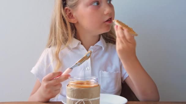 Niño Comiendo Pan Crujiente Con Mantequilla Maní Sentado Cocina Casa — Vídeos de Stock