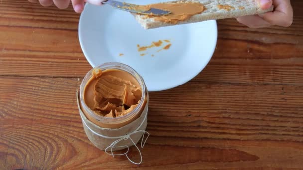 Criança Comendo Pão Crocante Com Manteiga Amendoim Sentado Cozinha Mesa — Vídeo de Stock