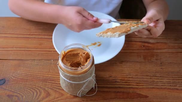 Barn Äter Knäckebröd Med Jordnötssmör Trä Bord Hem Kök Skolflicka — Stockvideo