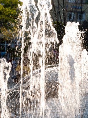 Water splashes in fountain on a sunny day on city street. Summer heat concept, travel photo.