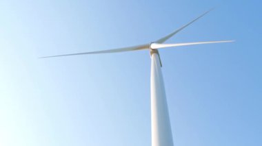Rüzgar türbini açık mavi gökyüzü arka planında dönüyor. Yerel çevre dostu güçlü dönüştürücü çiftliği temiz yenilenebilir rüzgar enerjisi üretiyor. Yeşil elektrik ekolojik arka plan tarımsal ekran koruyucu 4K