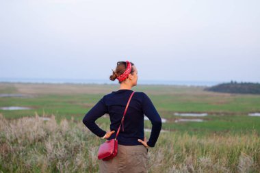 Sonbahar günbatımında kırmızı bandanalı güzel bir hippi kadın. Kendine güveni tam bir genç bayan bakışı. Milenyum kızı tek başına şık, yaşam tarzı özgün bir fotoğraf. Tek başına seyahat eden gerçek insanlar.