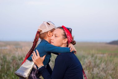Anne ve kızı doğa manzarasında kucaklaşıyorlar. Anne ve çocuk akşam vakti dışarıda yürüyorlar. Aşk, ilgi, arkadaşlık, stres, ilişki kavramı.