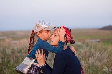 Anne ve kızı doğa manzarasında kucaklaşıyorlar. Anne ve çocuk akşam vakti dışarıda yürüyorlar. Aşk, ilgi, arkadaşlık, stres, ilişki kavramı.