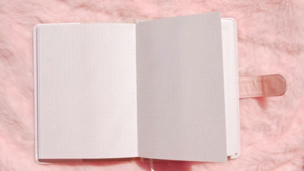 ピンクのフェイクファーのフラットレイにブランクノートモックアップ コーラルふわふわのフェミニンな生地の背景トップビュー 女性のブログは 繊維表面のメモ帳のコピースペーステキストのサインデザインをバラ ホワイトスケッチブックテンプレート — ストック動画