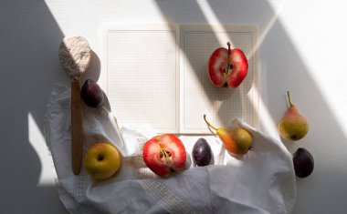 Sonbaharda bembeyaz keten masa örtüsünün üzerine açık yemek kitabı kırmızı elma armudu serpiştirirdi. Boş yemek tarifi defteri Şükran Günü tatili sağlıklı gıda malzemeleri. Moda mevsimlik meyveler.