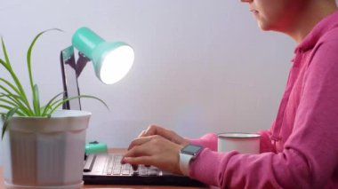 Laptop klavyesinde yazan serbest çalışan bir kadın. Evden çalışmak, uzaktan e-öğrenme ofisi. Öğrenci kız, internetten kahve içip video konferansı dinliyormuş. Millennial iş kadını masası.
