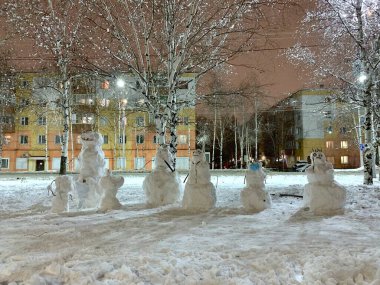 Karla kaplı bir grup kardan adam. Büyük ve küçük, korkutucu ve komik, biri tıbbi koruyucu maskeli..