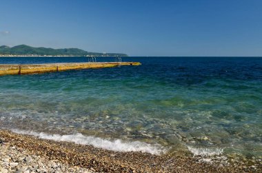 Mavi denizi gören deniz manzarası ve şafak ışıklarında çakıl taşı kıyısından gelen bir sıçrama ile köpüklü dalgalar..
