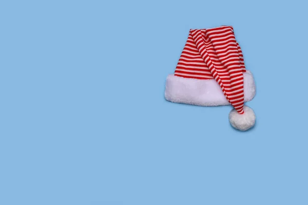 红白条纹圣诞老人帽 狂欢节头饰与白色毛皮和华丽 隔离在浅蓝色的背景 顶部视图 — 图库照片