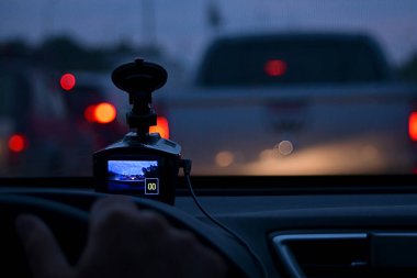 Arabadaki DVR ekranı, direksiyondaki elin bir parçası, durdurulan arabanın sıfır hızını tamir ediyor. Yolda, trafik sıkışıklığı sırasında, diğer arabaların arasında. Akşamları, iş çıkışı..