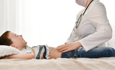 Mutlu bir çocuk karın duvarı muayenesi sırasında bir doktor tarafından güler..