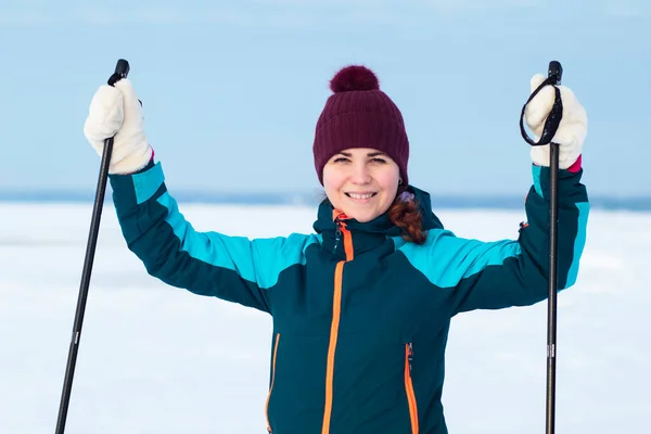 Счастливая позитивная женщина катается на лыжах зимой теплая одежда и шляпа на открытом воздухе в холодный солнечный день, улыбаясь — стоковое фото