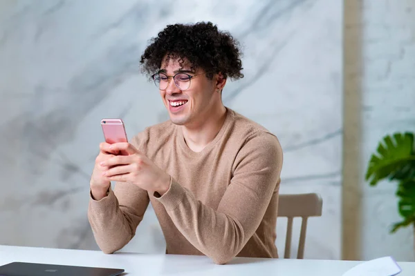 Retrato de cara positivo feliz bonito em óculos, jovem homem alegre está usando gadget, olhando para a tela de seu telefone celular, conversando nas mídias sociais no smartphone, digitando uma mensagem, sorrindo. — Fotografia de Stock