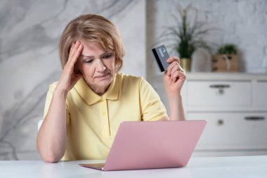 Sinirli, üzgün, yaşlı, yaşlı, emekli bir kadın. Endişeli bir kadın. İnternetten ödeme, satın alma, kredi kartı ödemeleri, dizüstü bilgisayar ekranına bak. İnternet dolandırıcılığı