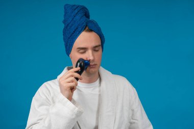 Gözleri kapalı yakışıklı genç bir adam uyanır ve sabahın erken saatlerinde bornoz ve kafasında havluyla yüzünü tıraş etmeye çalışır. Günlük rutin. Uyku eksikliği, uykusuzluk.