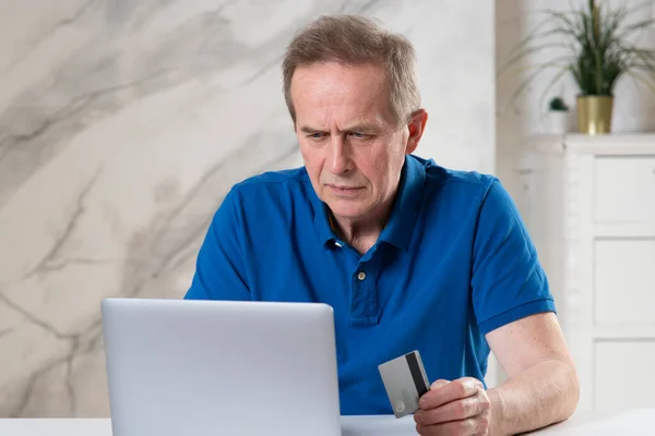 Portrait of handsome senior elderly retired man with laptop computer holding credit bank card, paying ordering in online internet store, shop at home, doing secure payment. Online shopping concept Royalty Free Stock Photos