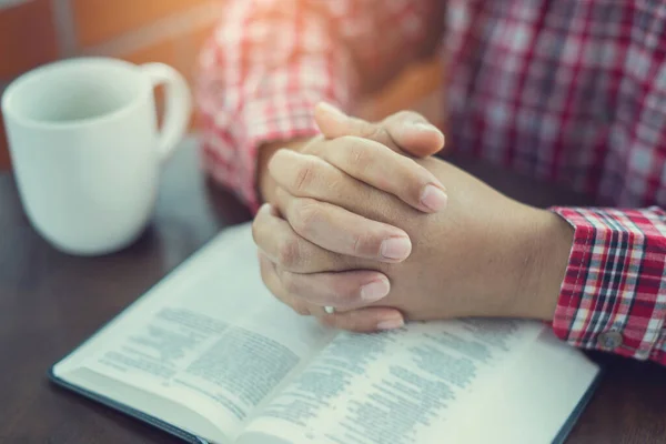 Christian hand while praying and worship for christian religion with blurred of her body background, Casual man praying with her hands together over a closed Bible. christian background. freedom.