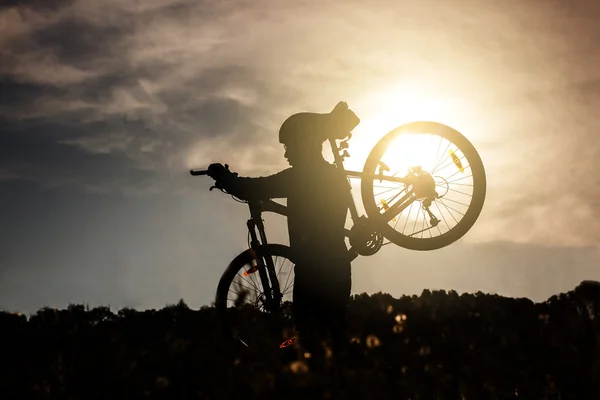 Sziluettjét férfi kerékpáros könyv biciklijét napkeltekor. — Stock Fotó