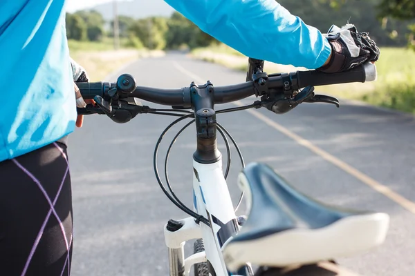 Hands in gloves holding handlebar of a bicycle on road. — Stock Photo, Image