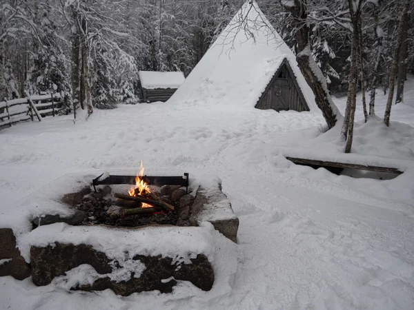 Wooden house in winter forest. Lapland house. House in the snow and bonfire.