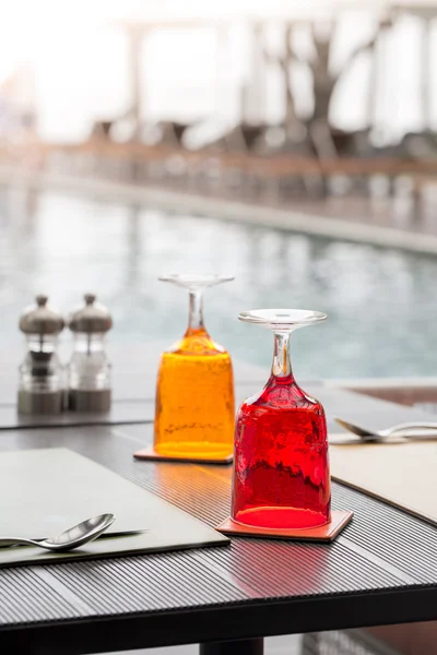Czerwony i żółty szklankę wody na stole i luksusowe zakwaterowanie w pobliżu swimm — Zdjęcie stockowe