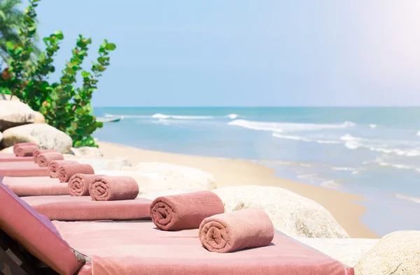 Leere Liege mit eingewickelten Handtüchern an einem schönen Strand Stockbild