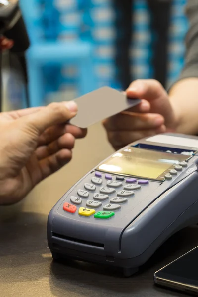 Máquina de cartão de crédito na mesa com mão pagando por cartão de crédito — Fotografia de Stock