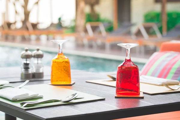 Verre d'eau rouge et jaune sur table de luxe près de la baignade — Photo