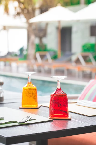 Vetro rosso e giallo di acqua sulla tavola di lusso impostazione vicino a nuoto — Foto Stock