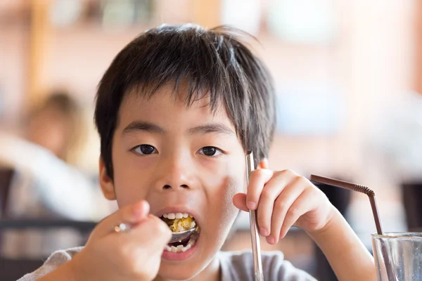 Pequeño niño comiendo su comida en el restaurante —  Fotos de Stock