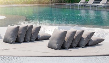 Rahatlatıcı üzerinde gri yastık yatak yüzme havuzunda güneşli günde