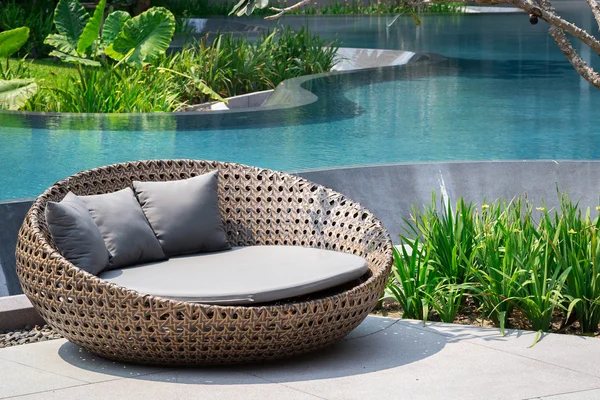Расслабляющий диван из ротанга у бассейна Лицензионные Стоковые Фото