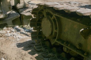 Bir yıkım alanındaki engebeli, çamurlu kazı alanının yakın çekimi. Arka planda enkaz ve beton parçaları görülüyor.